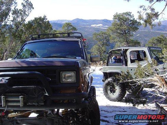 1986 Ford Bronco II front 3/4 view with winch and roof rack, parked next to another SUV