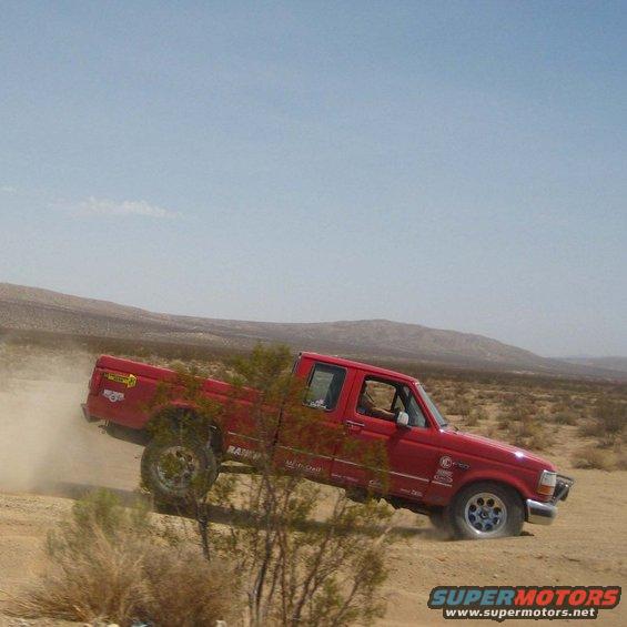 Red 1996 Ford F-150 pickup truck driving off-road