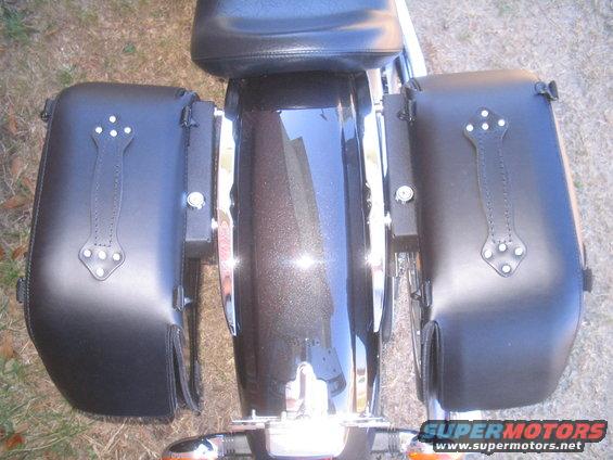 Black leather motorcycle saddlebags with decorative straps and studs, attached to a dark metallic fender