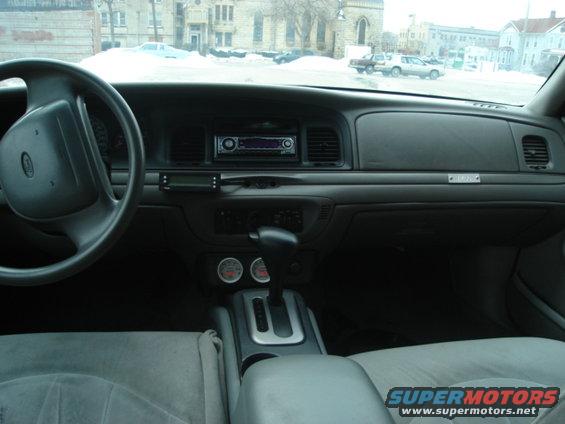2000 Ford Crown Victoria interior with gray seats, dashboard, steering wheel, and aftermarket radio