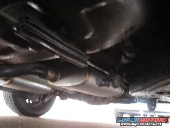 Undercarriage view showing dual exhaust mufflers and pipes, with a tire visible on the left