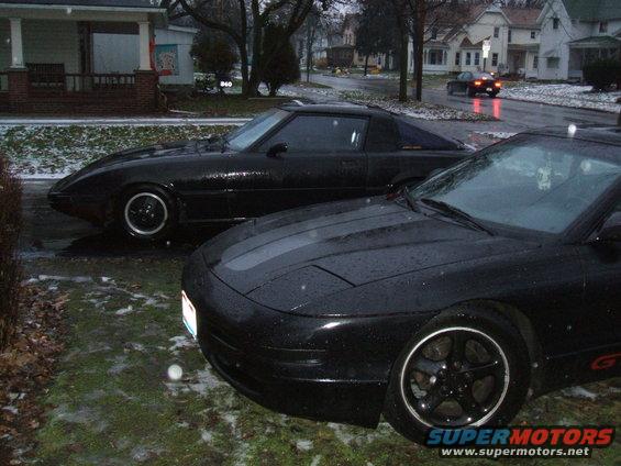 1983 Mazda RX-7 and a Ford Probe parked outside in the rain