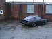 1983 Mazda RX-7 - A black 1983 Mazda RX-7 is parked in an empty lot next to a brick building.