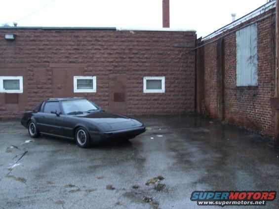1983 Mazda RX-7 coupe parked in a wet, urban area