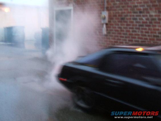 Black 1983 Mazda RX-7 from the rear, emitting smoke