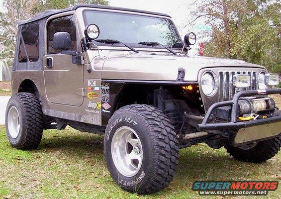 Tan Jeep Wrangler with aftermarket bumper and winch. Has several stickers on the fender