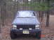 1988 Jeep Comanche - Front view of a 1988 Jeep Comanche pickup truck parked outdoors among trees.
