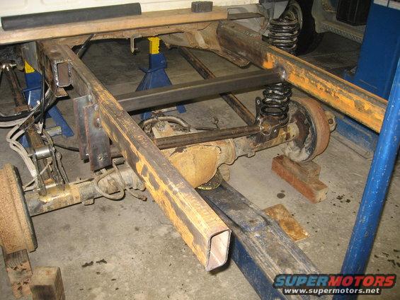 Truck frame and suspension with added metal bracing, viewed from rear