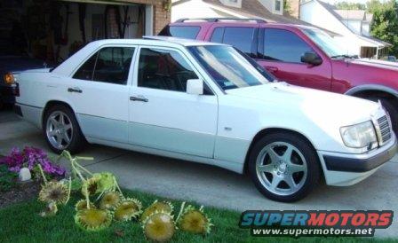 White Mercedes-Benz sedan parked in driveway next to a red SUV