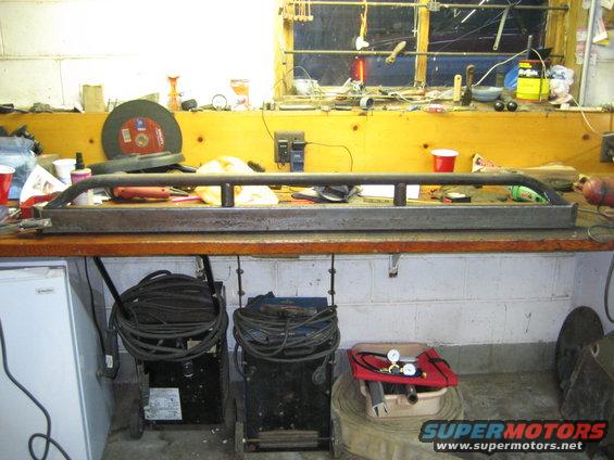 metal rock sliders on a workbench with tools and welding equipment