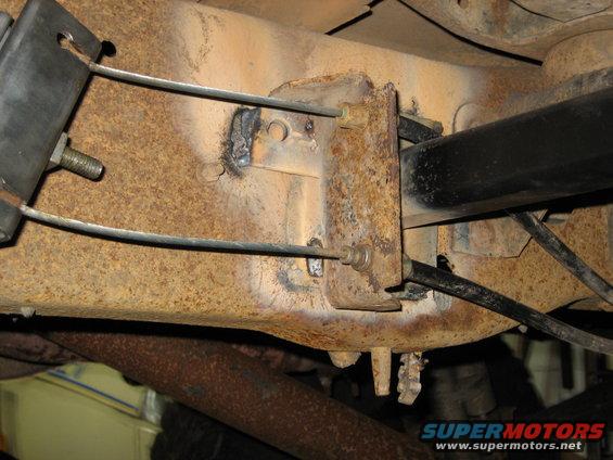 close-up of rusty vehicle frame with cables and suspension parts