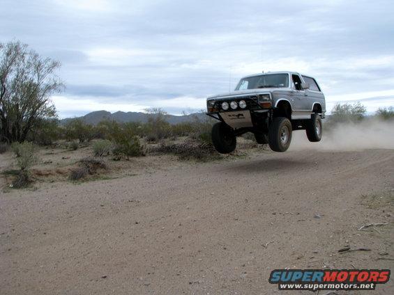 Silver 1980 Ford Bronco jumping in desert