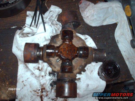 Greasy universal joint with cross and bearing caps, lying on a white cloth