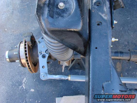 Close-up of a vehicle's front suspension assembly with a disc brake rotor and steering linkage