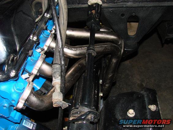 Engine exhaust headers and blue painted engine block with spark plugs visible