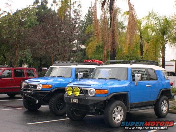 Two blue 2007 Toyota FJ Cruisers parked, one with yellow fog lights