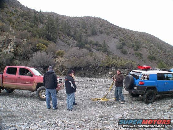 2007 Toyota FJ Cruiser and red pickup truck with people in a rocky area