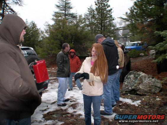 Two Toyota FJ Cruisers, one black and one blue, in a snowy wooded area with people standing around