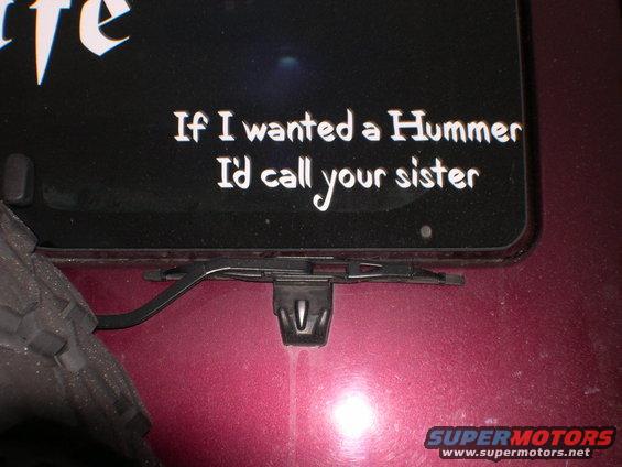 Sticker on a dark surface reads 'If I wanted a Hummer I'd call your sister'. Part of a tire and wiper mechanism visible