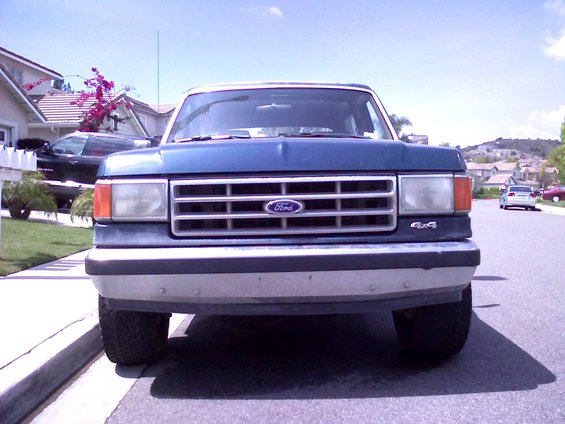 Front view of a blue 1986 Ford Bronco with a chrome grille and 4x4 badging