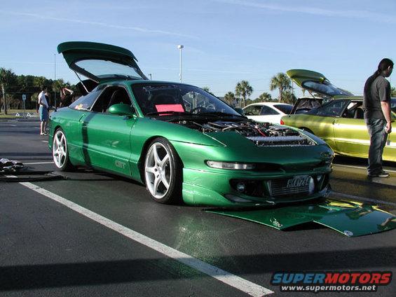 Green 1994 Ford Probe with hood and trunk open, parked next to a yellow car