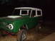 1974 Ford Bronco - This green Ford Bronco with a white top is parked outdoors at night, showing its front and side profile.
