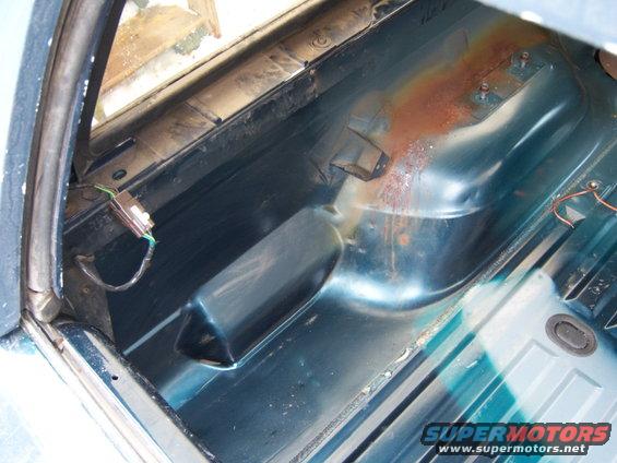 Interior floor pan showing rust and some wiring. The area appears to be the rear cargo space