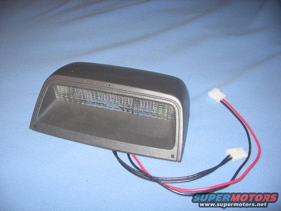 Car part, possibly a light, with red and black wires attached
