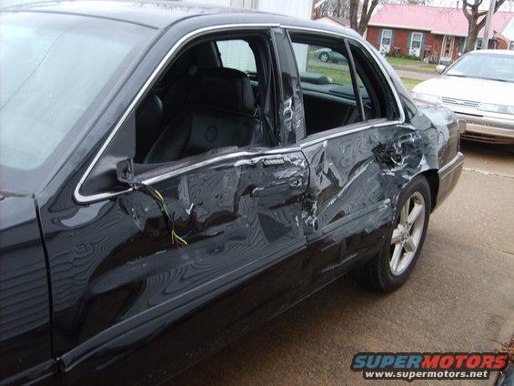 1993 Ford Crown Victoria side view with heavily damaged driver's side doors