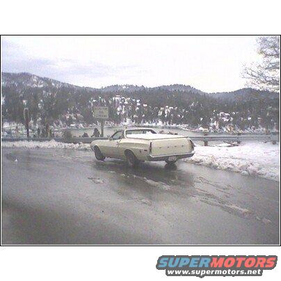 1972 Ford Ranchero parked on a wet road with snow on the sides, mountains in background