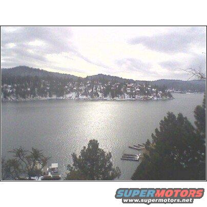 Lake Arrowhead scene with snow-covered hills and houses under a cloudy sky