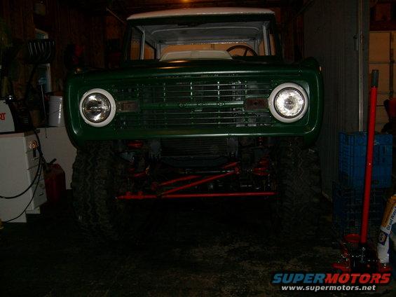 Front view of a green 1974 Ford Bronco with a white top, lifted suspension, and large tires