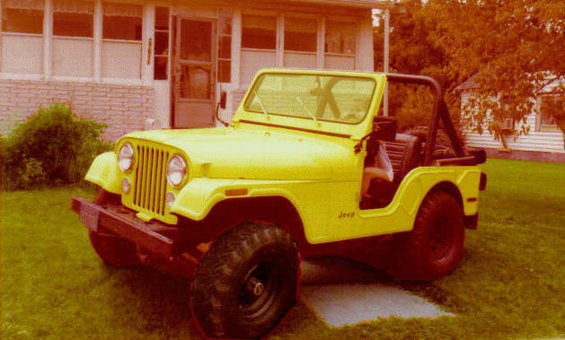Yellow Jeep CJ with black roll bar and off-road tires parked on grass