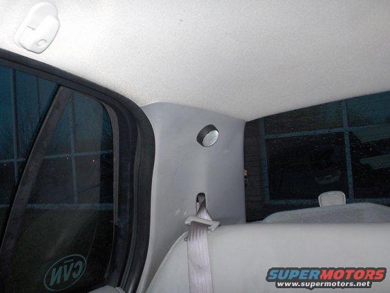 Interior rear pillar with a light fixture and seatbelt, viewed from the rear seat