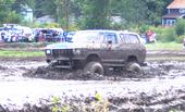 Muddy 4x4 truck driving through a mud pit