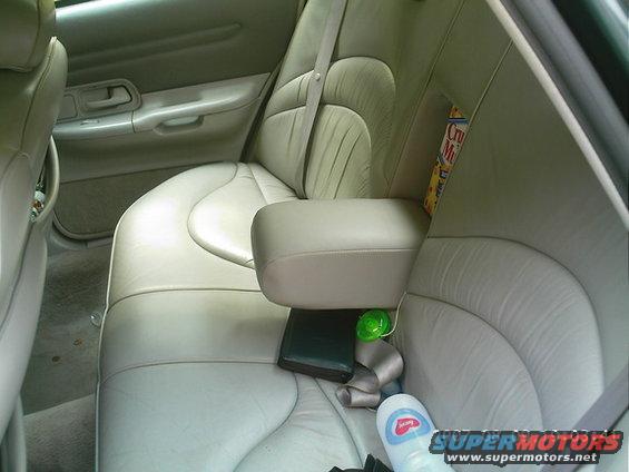 Back seat of a car with light-colored leather seats, armrest, and a box of cereal on the side