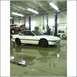 1994 Ford F-250 - A white coupe sits in a garage bay, while another vehicle is raised on a lift in the background.