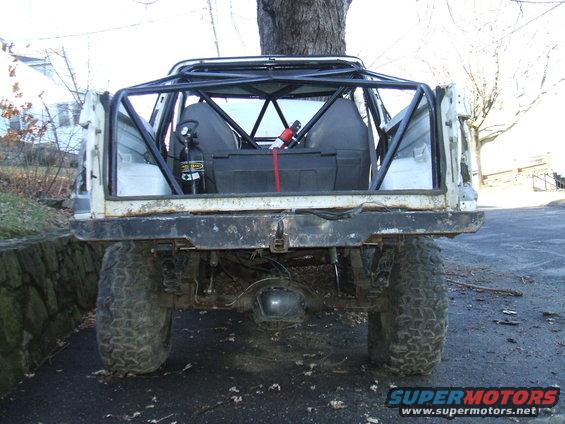 Rear view of a modified off-road vehicle with a roll cage, large tires, and a nitrous bottle inside
