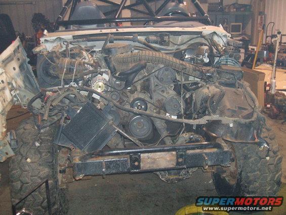 Front view of a disassembled 1995 Ford Bronco with engine exposed, showing the engine bay and front tires