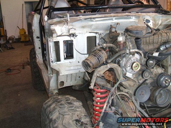 Disassembled vehicle engine bay with exposed engine components and red coil springs
