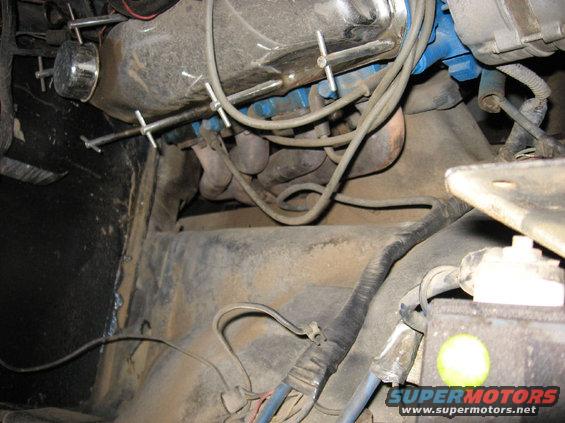 Engine bay with exhaust manifold, wiring, and battery visible