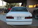 1993 Ford Taurus - The rear of a white 1993 Ford Taurus SHO is visible, parked under a covered area with various engines and equipment in the background.
