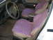1993 Ford Taurus - The interior of the vehicle features purple seat covers over tan upholstery, with a view of the steering wheel and dashboard.