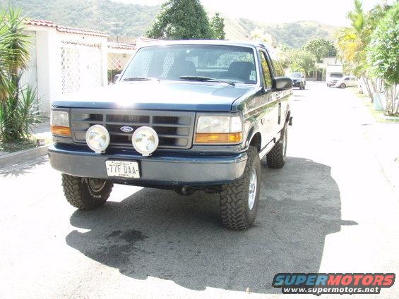 Blue Ford F-150 with aftermarket lights and off-road tires, front view