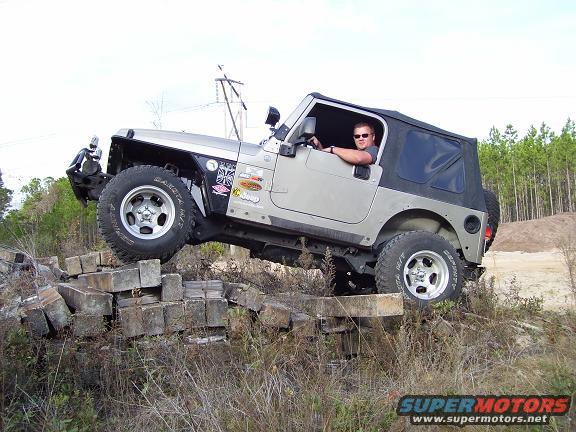 Silver Jeep TJ driving over concrete blocks off-road