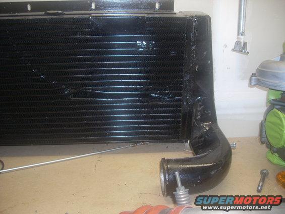 Black intercooler with black piping attached. Supermotors.net logo visible