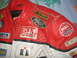 2005 Yamaha R1 - This close-up shows a red and white leather motorcycle jacket adorned with various racing sponsor patches.