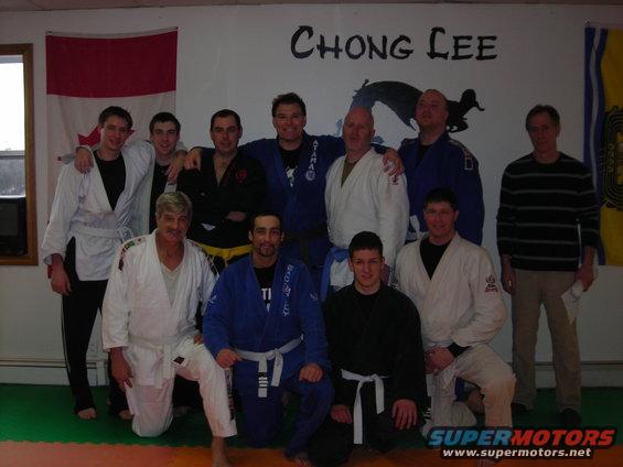 Group of martial artists posing in a dojo with 'CHONG LEE' painted on the wall
