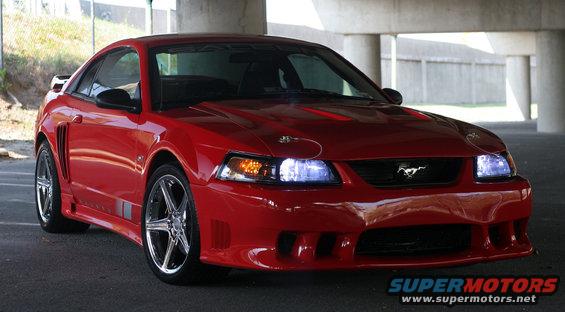 Red 2004 Saleen S-281SC Mustang coupe, front 3/4 view, clean condition, parked under a concrete overpass