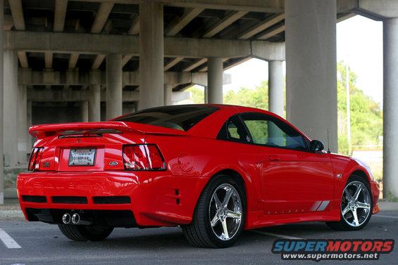 Red 2004 Saleen S-281SC coupe parked under an overpass, rear quarter view